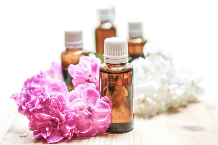Essential oil bottles with flowers on a wooden surface