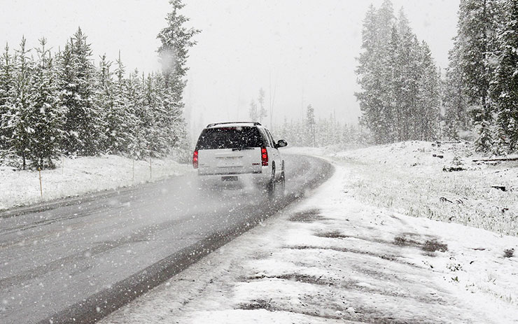 SUV driving down snow-covered road.