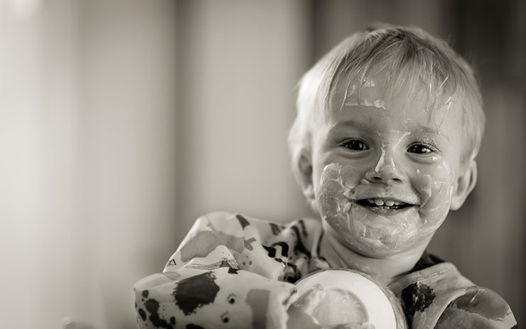 Black and white photo of a small toddler with lotion spread across his face.