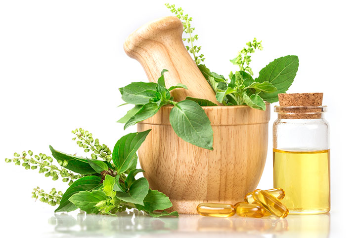 Mortar and pestle set surrounded by basil leaves and oil.