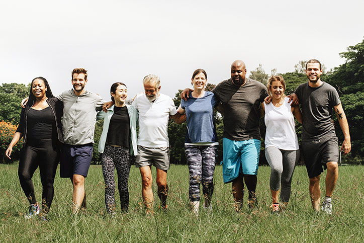 Diverse group of adults and older adults walk together across an open field.