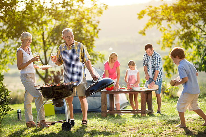 Happy family camping and cooking barbecue outside