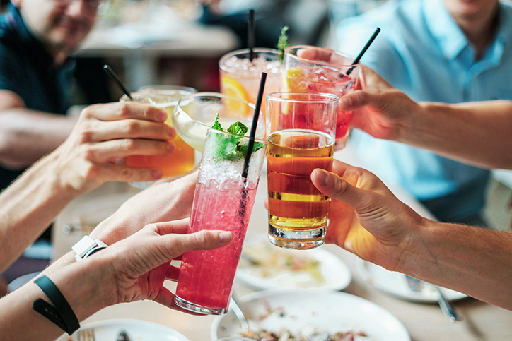 A group of hands holding alcoholic drinks for a cheers