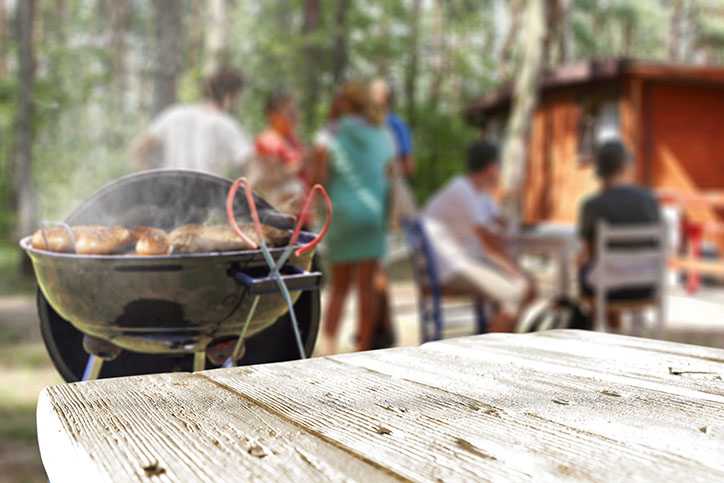 Food cooking on grill with family gathered in the background