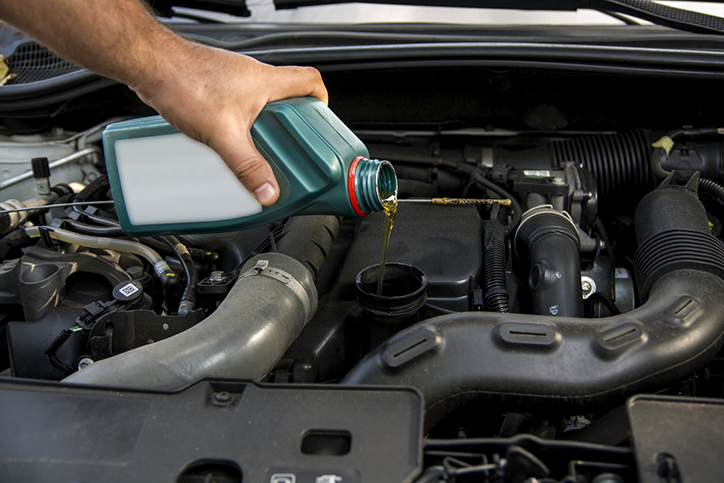 A person pouring motor oil into a car