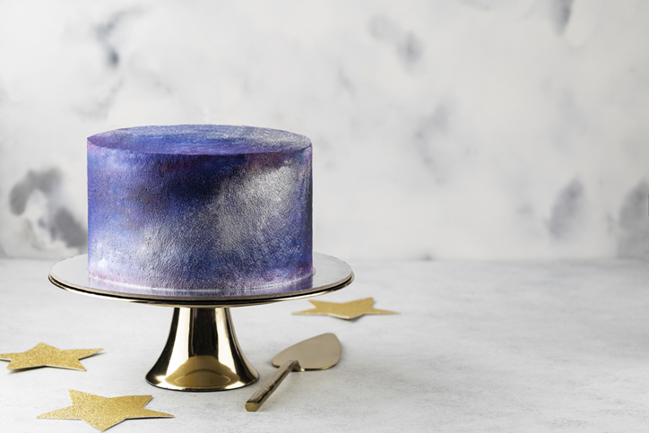 Cake with a metallic purple and blue finish sits on a cake stand.